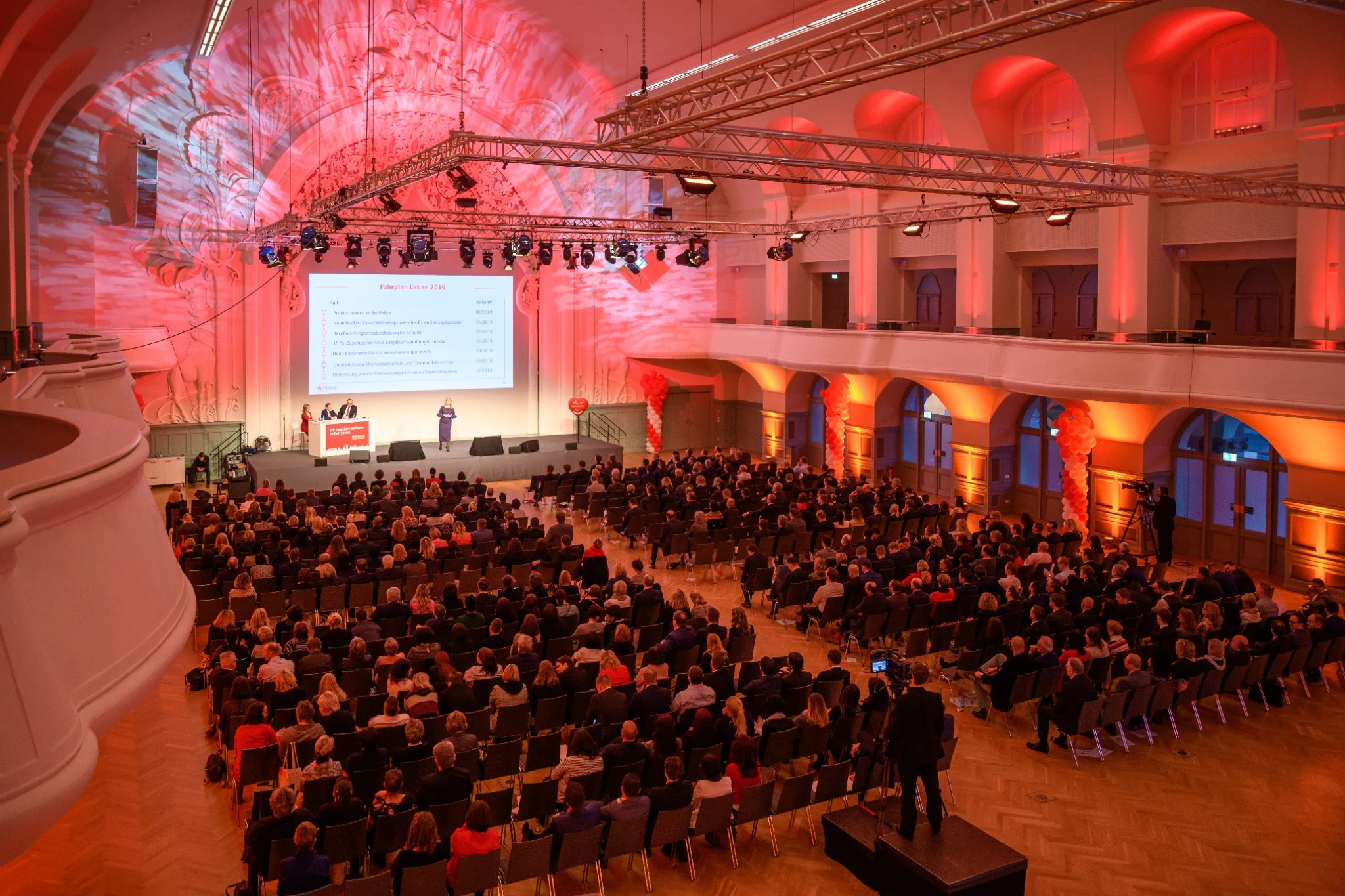 Kongresssaal mit Publikum, Bühne und großflächiger Projektion